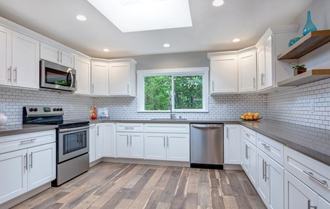 Clean and well-lit white kitchen interior with wood flooring.